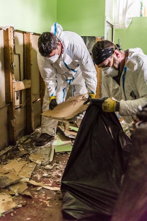 flood cleanup safety on display as volunteers in PPE clean up drywall